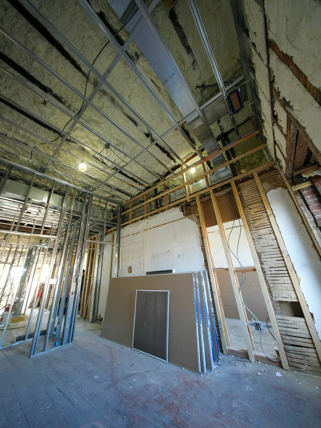 A three-story brownstone stands in mid-transformation, captured at the raw and honest “before” stage of a full interior renovation. These images document a moment that usually disappears once the walls are closed and the finishes are installed — exposed framing, stripped ceilings, rough staircases, and open corridors that reveal the building’s original structure and hidden history. Light spills in through skylights and tall windows, cutting through layers of dust and unfinished surfaces, creating a quiet contrast between decay and renewal. The space feels both industrial and intimate: narrow